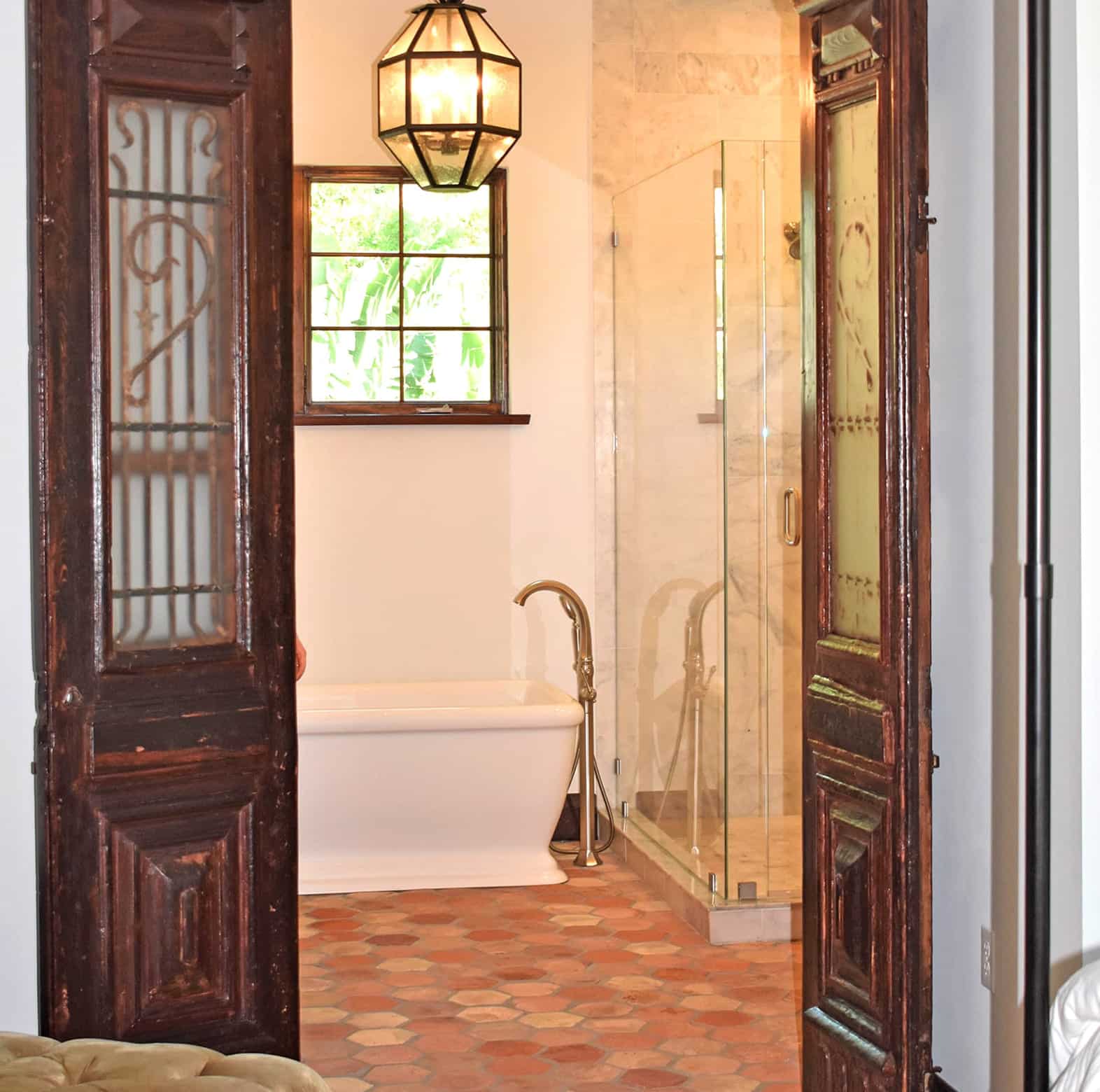 Vintage bathroom with clawfoot tub, glass shower, and wood doors