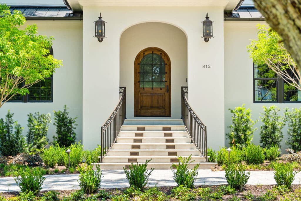 Elegant arched entryway with wooden door and landscaped steps