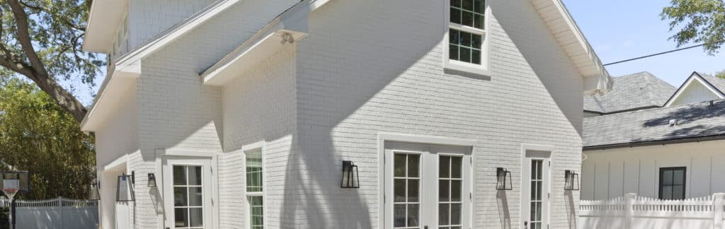 White brick house exterior with French doors and lanterns