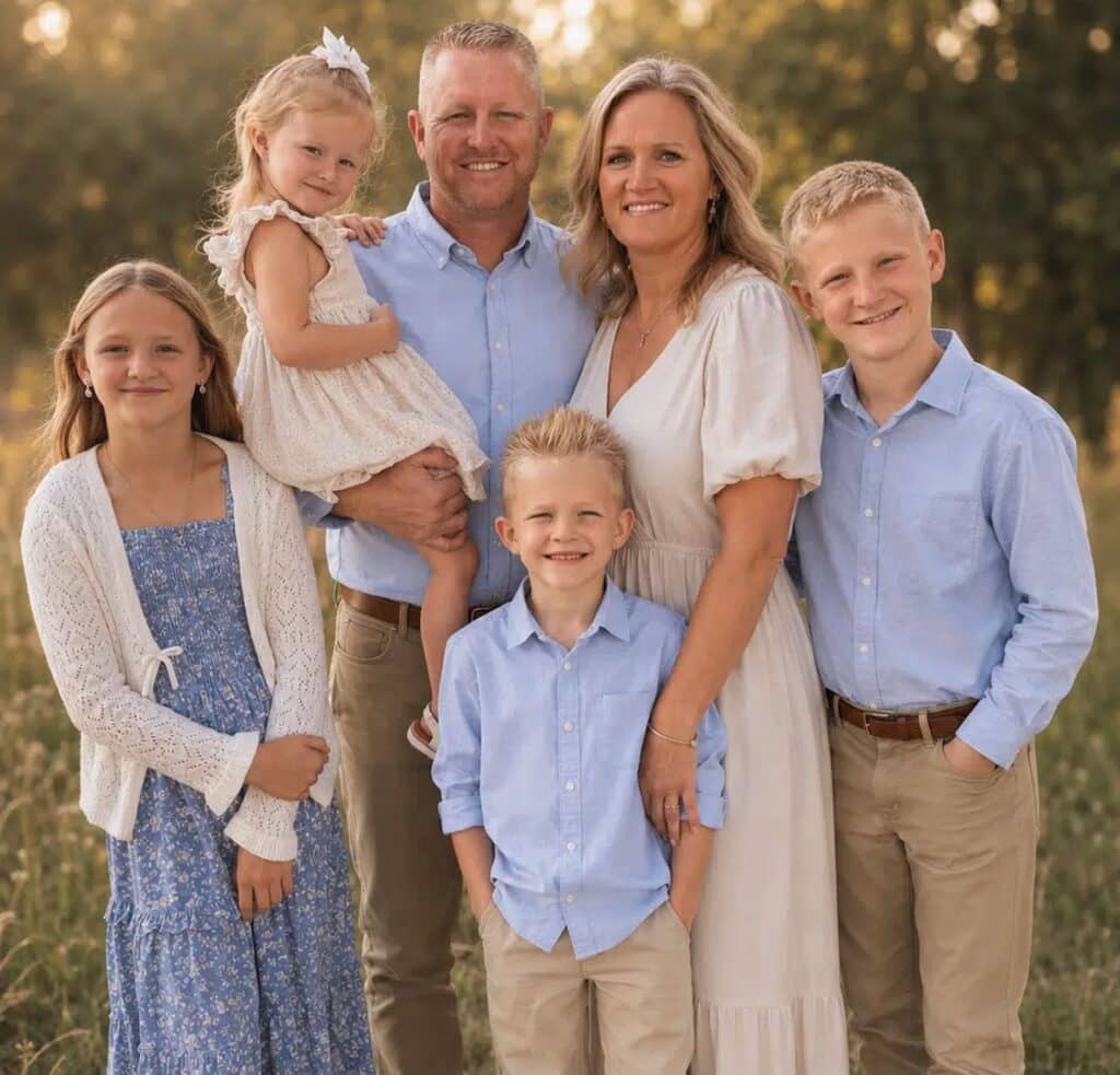 Smiling family of six posing outdoors at sunset